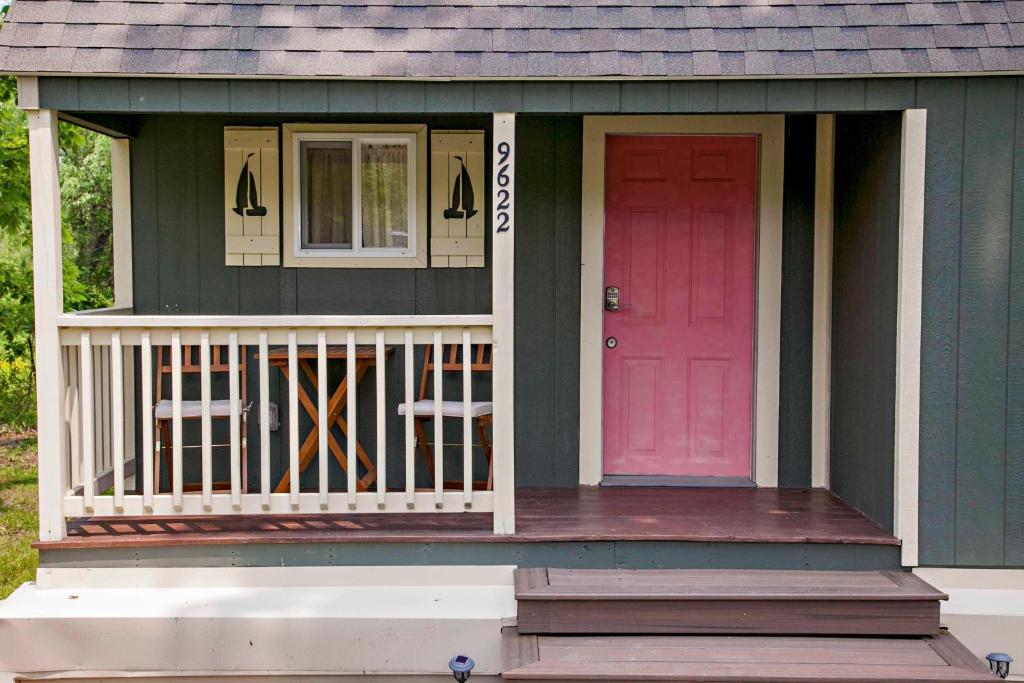 a green house with a pink door and a porch at Lil Hickory in Hammondsport