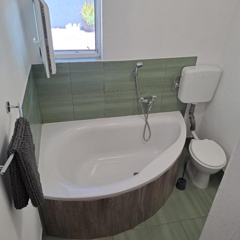 a bathroom with a bath tub and a toilet at Apartma Kolpa Krasinec in Gradac