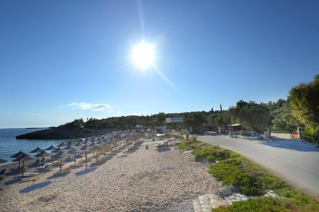 a beach with umbrellas and chairs and the ocean at Rozalia Studios in Syvota