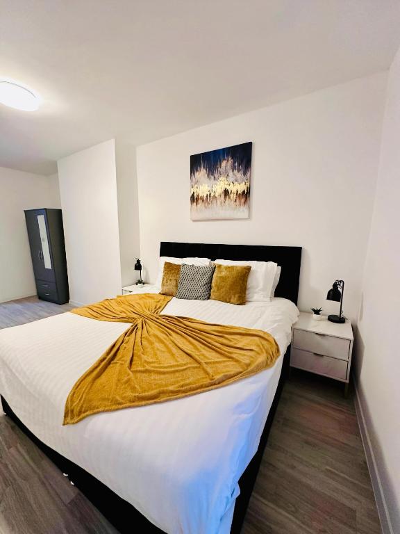 a bedroom with a large bed with a yellow blanket on it at Family & Contractor Haven Suites Mexborough in Mexborough
