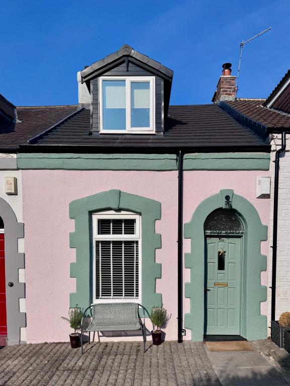 a pink and green house with a bench in front at Renas Seahaven Cottage in Cullercoats