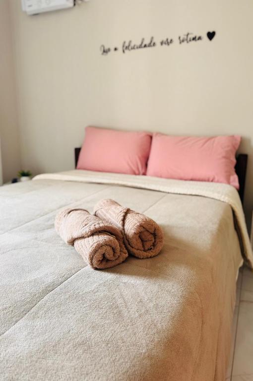 a towel laying on a bed with pink pillows at Suítes da Orla Hospedagens in Arraial do Cabo