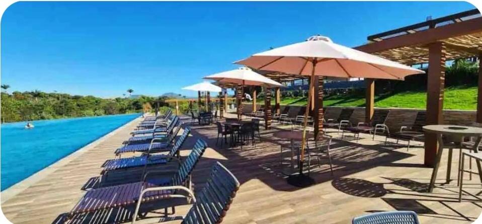 a row of chairs and umbrellas next to a pool at Apto 1qto Quinta Santa Bárbara in Pirenópolis