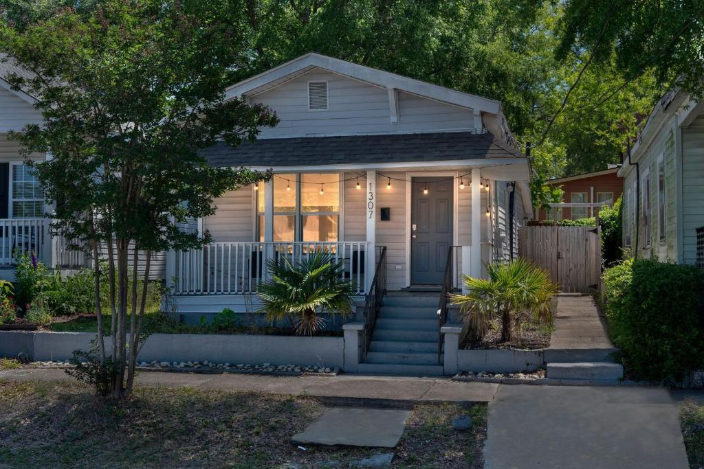 uma casa branca com um alpendre com uma porta em Mod Cottage em Wilmington