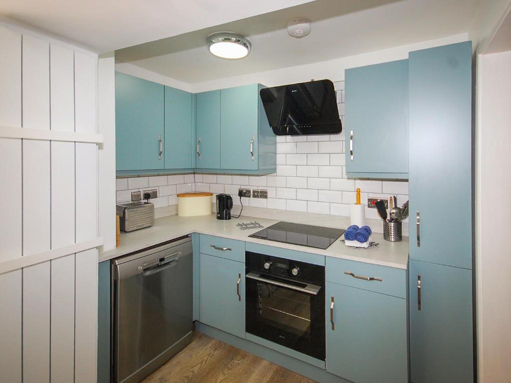 a kitchen with blue cabinets and a stove at Wherry Cottage in Wells next the Sea