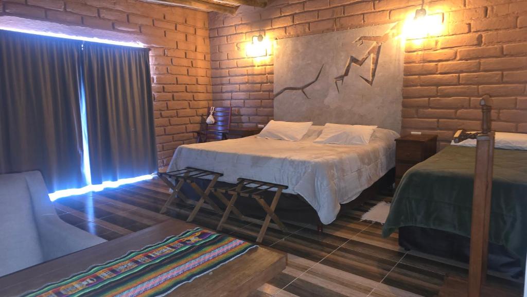 ein Schlafzimmer mit zwei Betten und einer Ziegelwand in der Unterkunft EL Viejo Algarrobo Fiambala in El Puesto