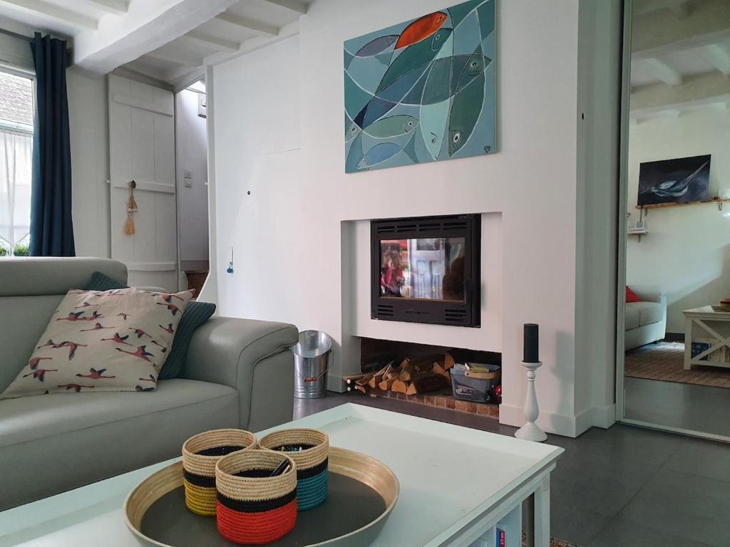 un salon avec un canapé et une cheminée dans l'établissement Bienvenue aux Bateliers, à Saint-Valery-sur-Somme