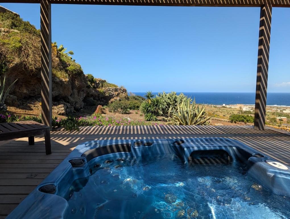 a hot tub on a deck with the ocean in the background at Dammusi Musa in Pantelleria