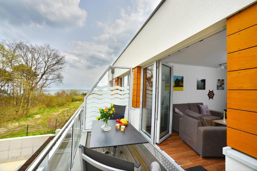 een kamer met een balkon, een bank en een tafel bij Ferienwohnung Meeresblick in Juliusruh