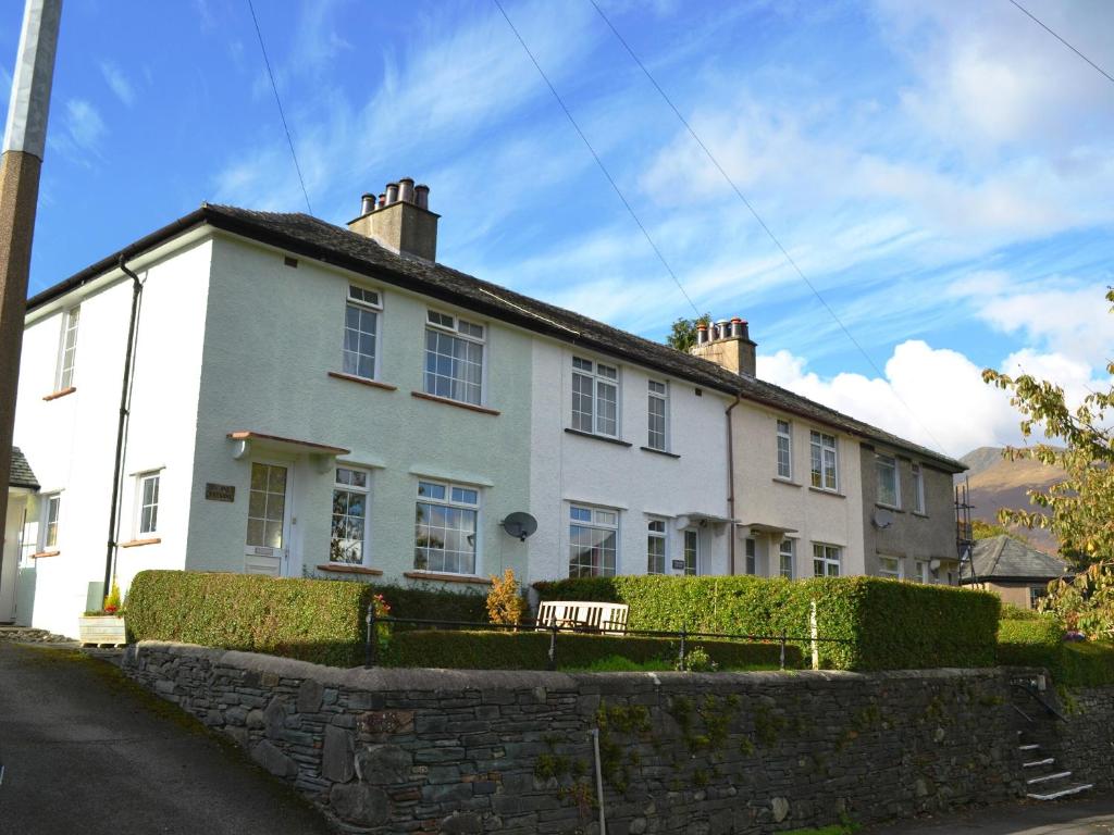 a white house with a bench in front of it at Valentine Cottage in Keswick