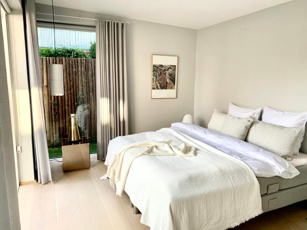 a white bedroom with a large bed and a window at Stylish 70'S Villa With Forest And Lake View In Ry in Ry