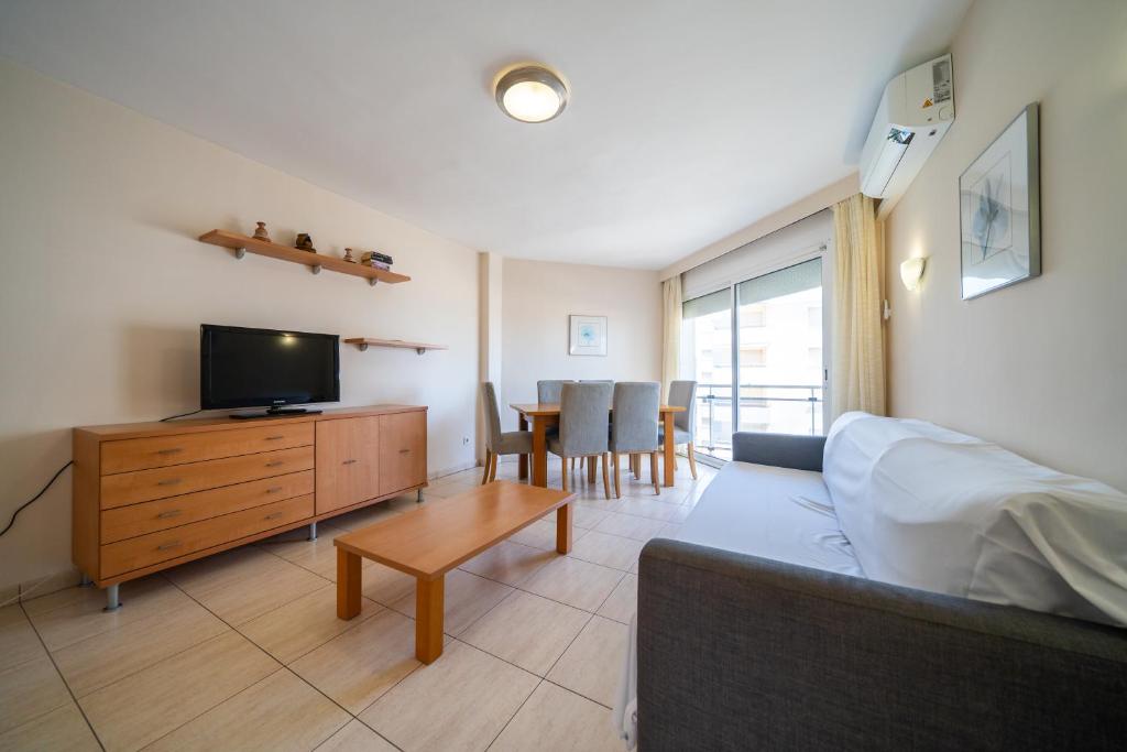 a living room with a couch and a tv and a table at Apartaments Lamoga - Boabi in Torredembarra