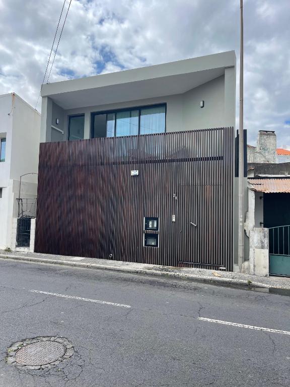 a building with a wooden fence next to a street at Toes in the sand in São Roque