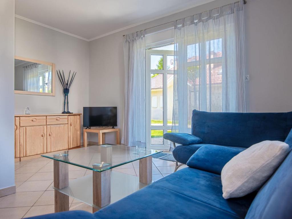 a living room with a blue couch and a glass table at Holiday Home Domek Joanna-1 by Interhome in Łeba