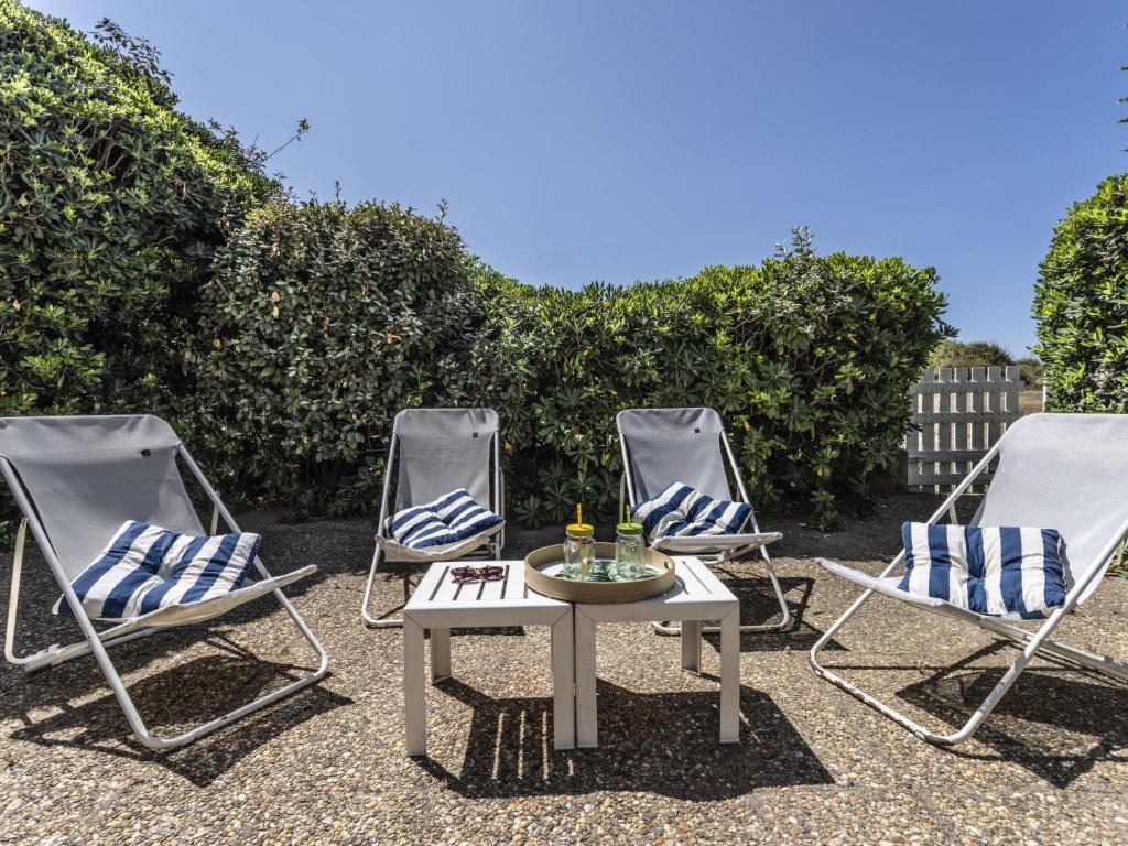 un groupe de trois chaises et d'une table sur une terrasse dans l'établissement Apartment Les Maisons sur la Plage-3 by Interhome, au Cap d'Agde