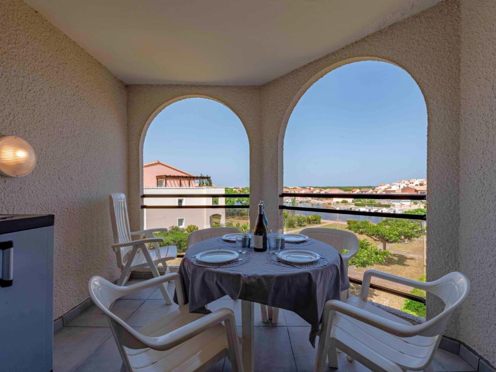 une salle à manger avec une table et des chaises et deux fenêtres dans l'établissement Apartment Caraibes-1 by Interhome, au Barcarès