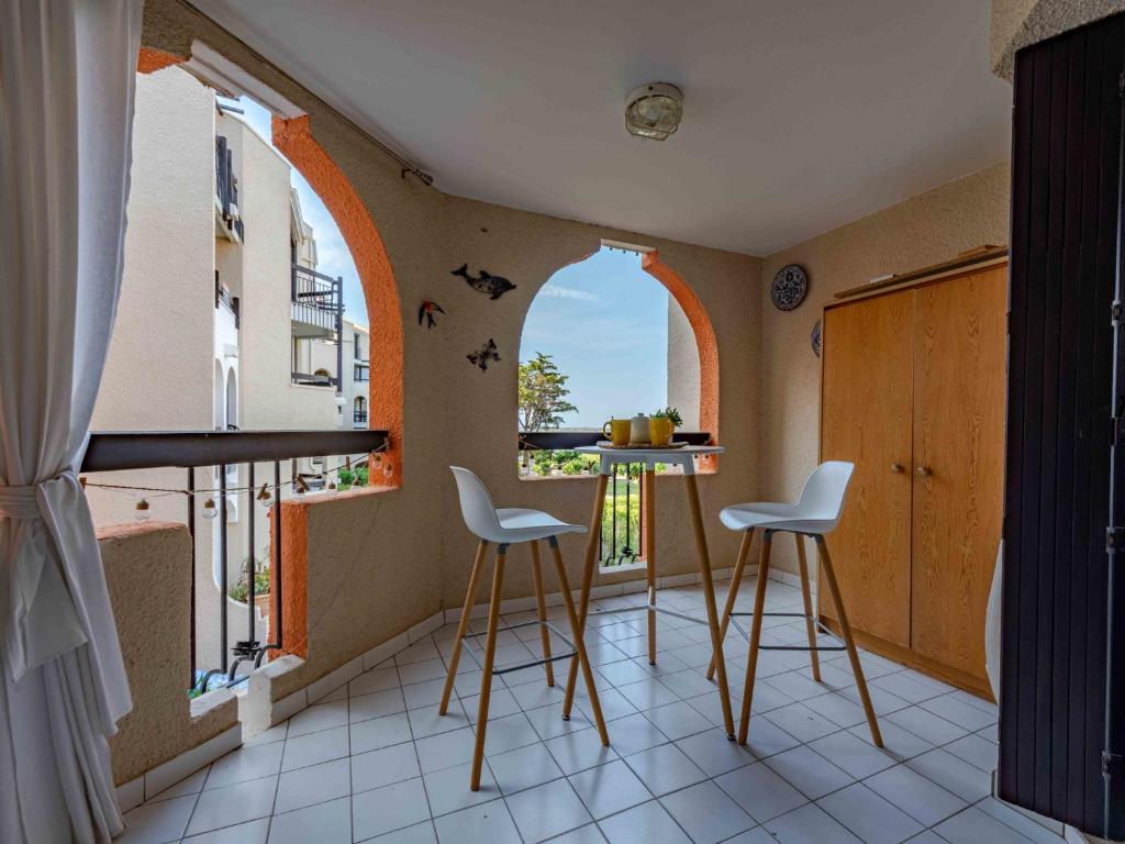 une cuisine avec deux tabourets et une fenêtre cintrée dans l'établissement Apartment Dominica-5 by Interhome, au Barcarès