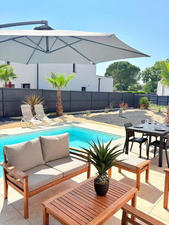 - une terrasse avec un canapé et un parasol à côté de la piscine dans l'établissement Somptueuse villa luxueuse piscine jacuzzi, à Teyran