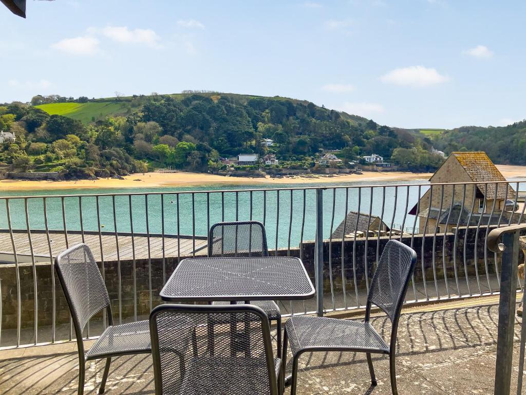 einen Tisch und Stühle auf einem Balkon mit Blick auf einen Wasserkörper in der Unterkunft Marine Mews 3 - Cottage in Salcombe