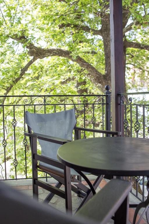 a table and a chair on a balcony with a tree at Φιλυρέα Apartments - Room 4 in Zagora