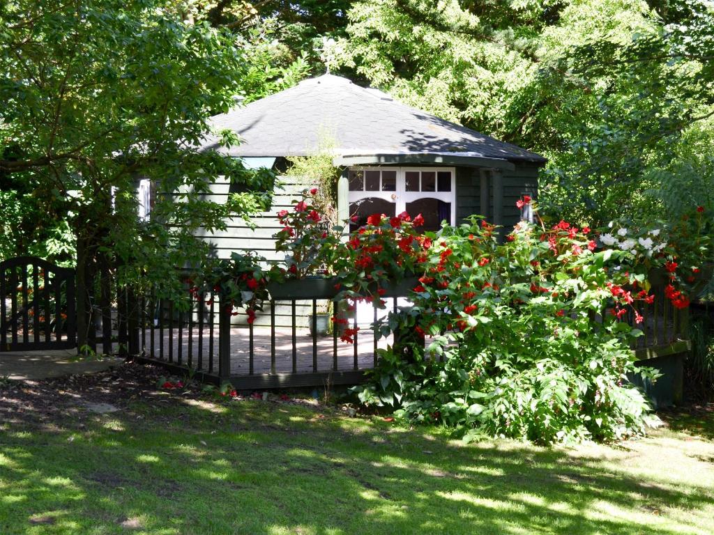 a gazebo behind a fence with red flowers at Beach Retreat - Ukc2322 in St Ives