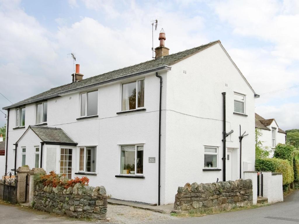 a white house with a stone wall at Bridge Cottage in Braithwaite