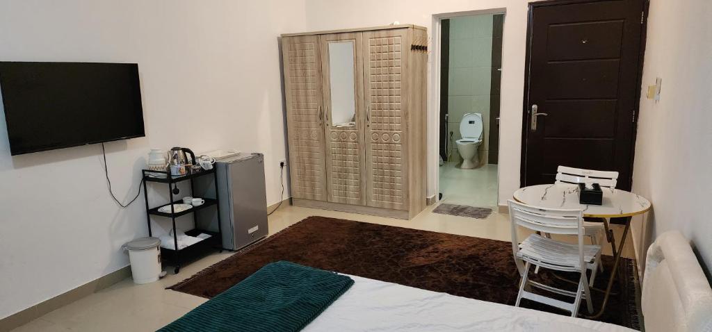 a room with a bathroom with a toilet and a television at Muscat Airport Guesthouse All Private Ensuite Rooms in Muscat