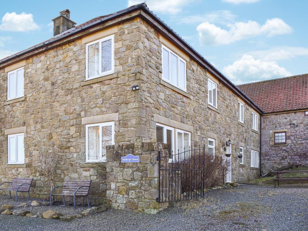 un vieux bâtiment en pierre avec deux chaises devant dans l'établissement Bamburgh House - Uk46435, à Belford