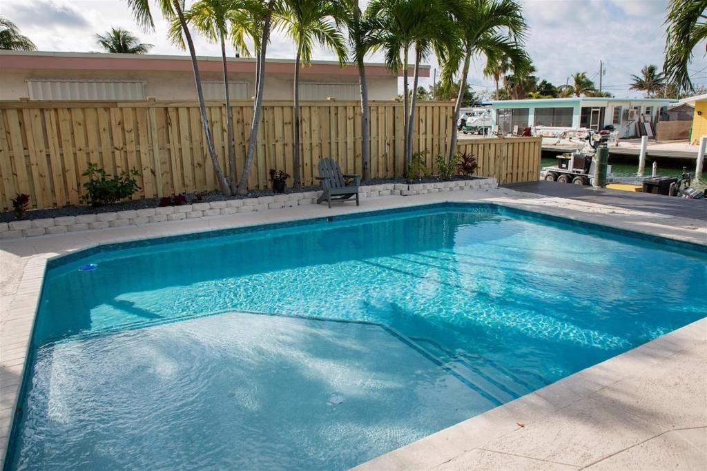 a large blue swimming pool with a fence and palm trees at Reel Deal - Waterfront Pool Home, 76' Dock in Marathon