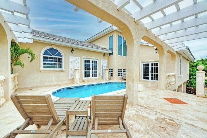 una casa con piscina y dos sillas en Reel Relaxin` - Luxury Waterfront Pool Home, 55' Dock, en Marathon