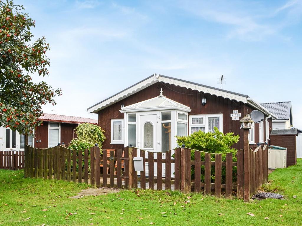 a house with a wooden fence in front of it at Enjoy Your Stay Cottage in Bessingby