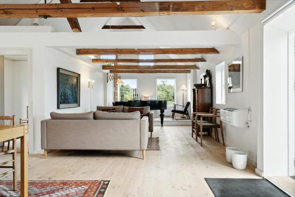 a living room with white walls and wooden ceilings at Renovated Estate With Private Beach in Roslev