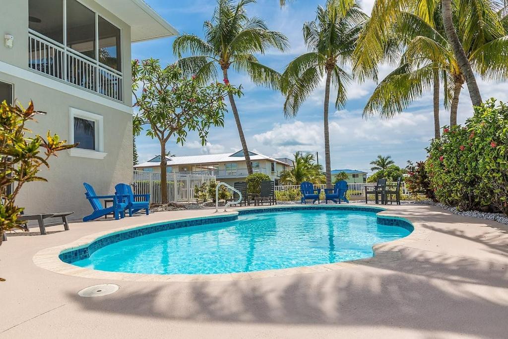 a swimming pool with blue chairs and palm trees at Sombrero Beach Beauty- Luxury Waterfront Pool Home, 50` Dock in Marathon