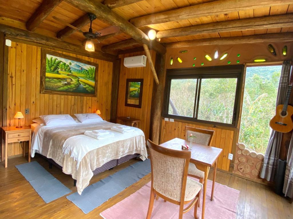 a bedroom with a bed and a table and a guitar at Cabana com vista para o canyon in Praia Grande