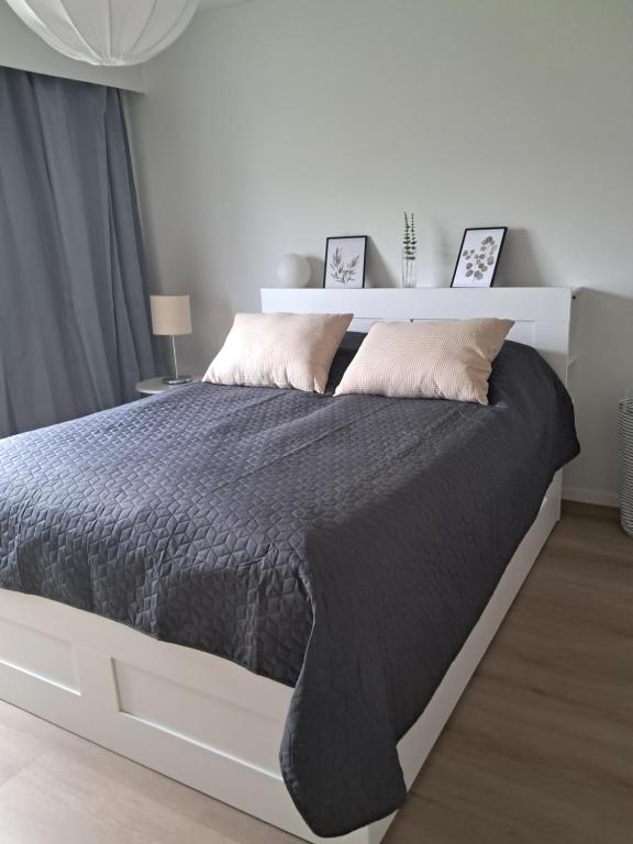 Un dormitorio blanco con una gran cama negra con almohadas. en Malmi apartment-3 rooms with a sauna, en Oulu