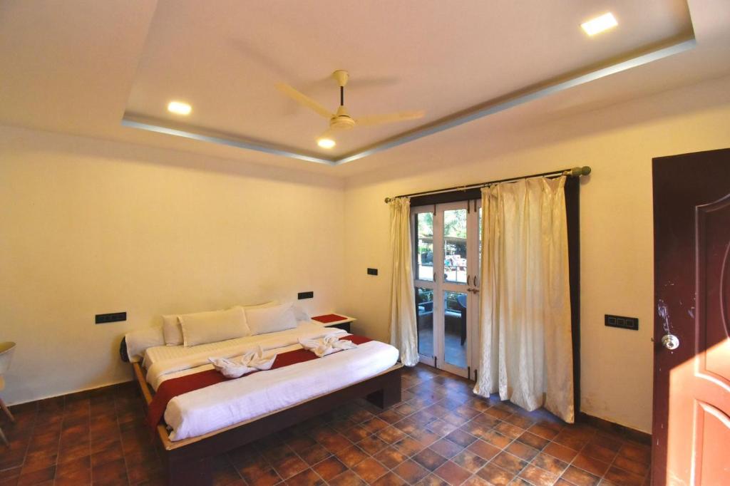 a bedroom with a bed in a room with a window at Golden Rice Resort & Cottages in Candolim