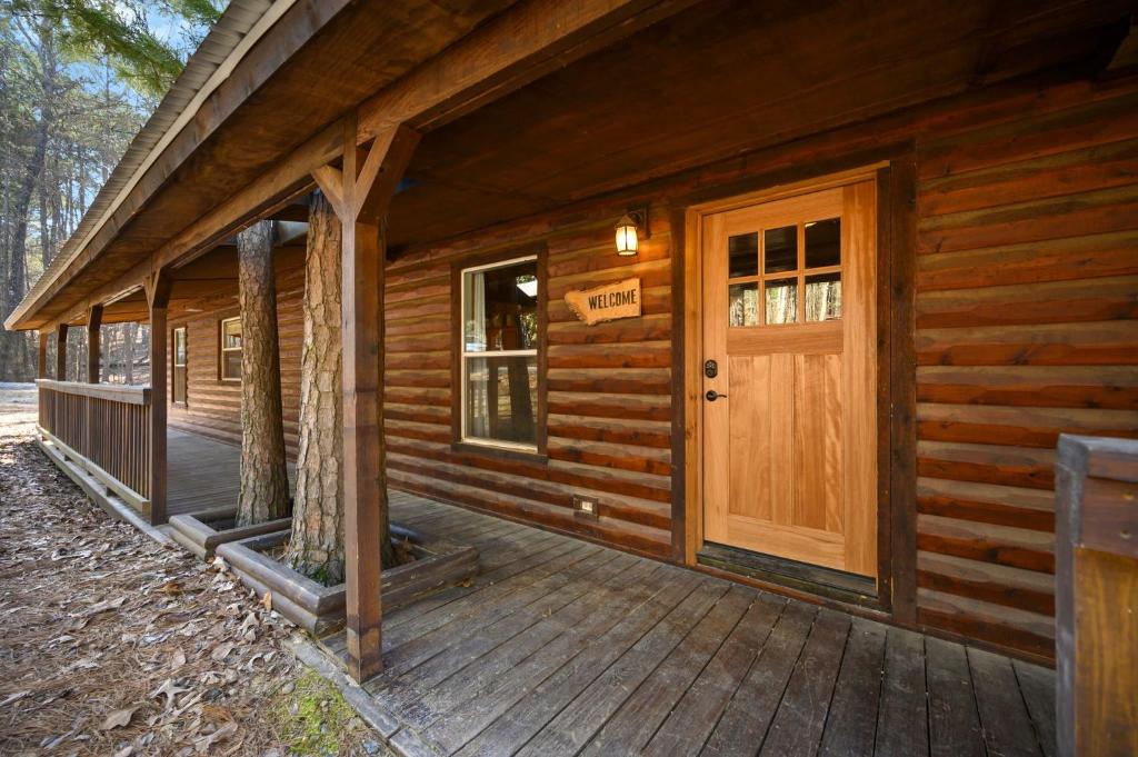 porche delantero de una cabaña de madera con puerta en Outlaw Rose Cabin - Family Fun with Hot Tub, en Broken Bow