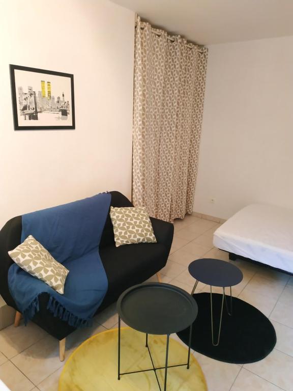 un salon avec un canapé et deux tables dans l'établissement Agréable studio entièrement équipé, à Périgueux