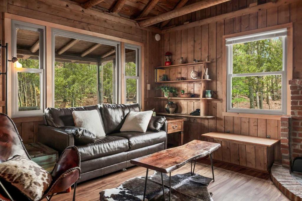 a living room with a leather couch and a table at Cozy w Fire Pit Grill Deck Screened Porch WiFi in Harpers Ferry