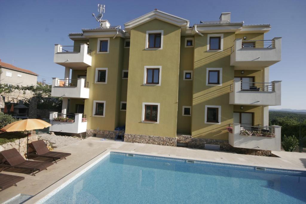 un edificio con piscina frente a un edificio en Apartments Salatić en Krk