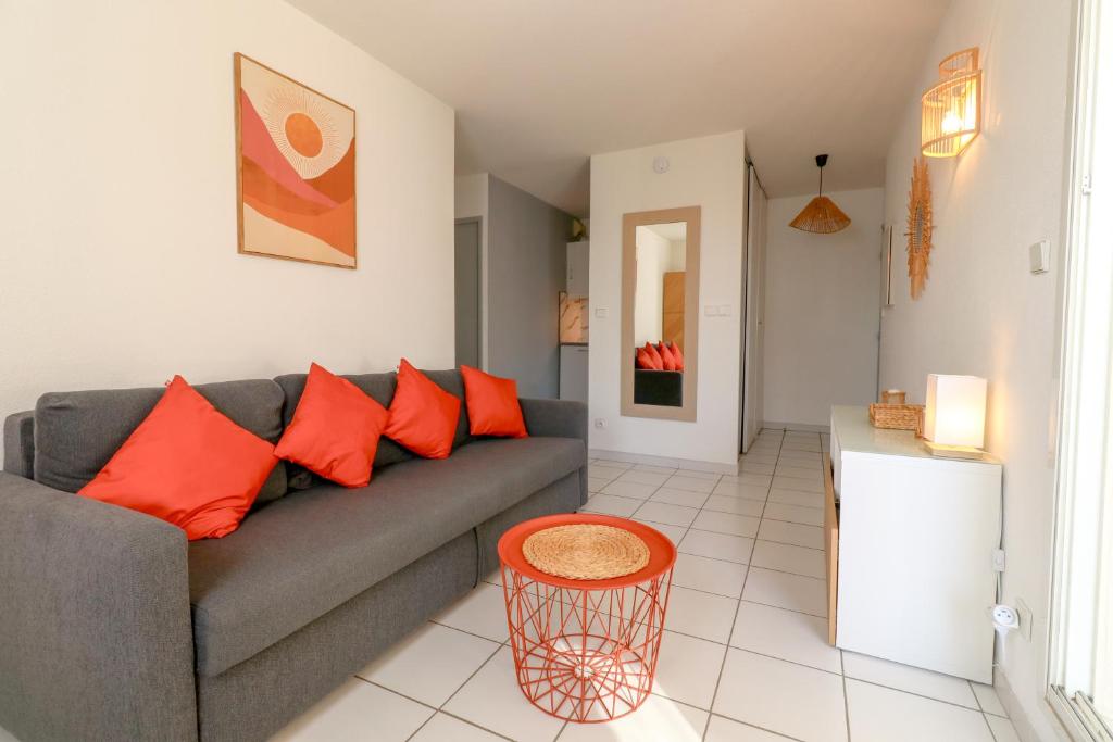 - un salon avec un canapé gris et des oreillers orange dans l'établissement Palmera by Pom, parking, piscine, au Cap d'Agde