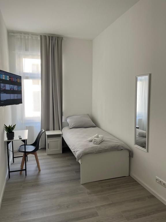 a white bedroom with a bed and a chair at Homburg-Residenz in Bad Homburg vor der Höhe