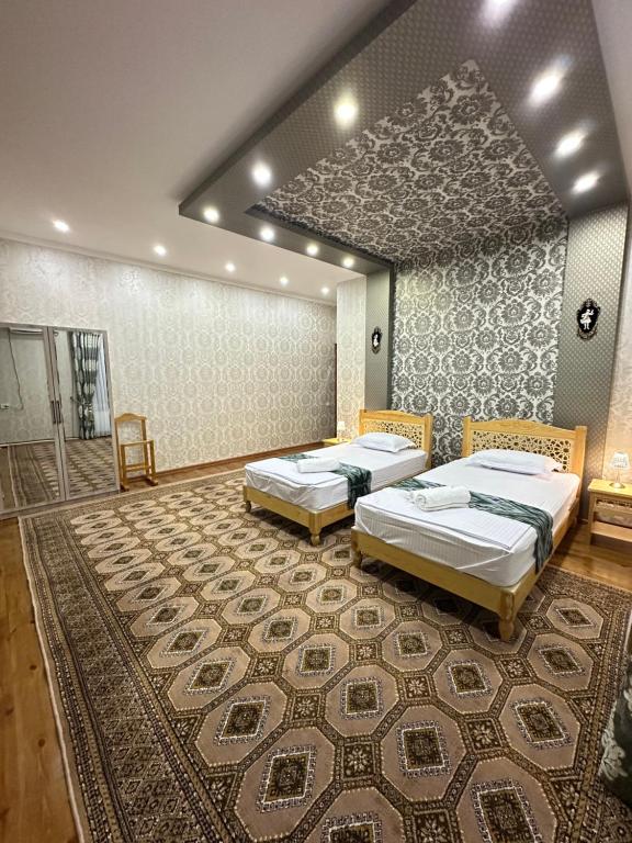 two beds in a room with a rug at Firdavsiy Guesthouse - Уютный Апарт-отель у озера in Bukhara