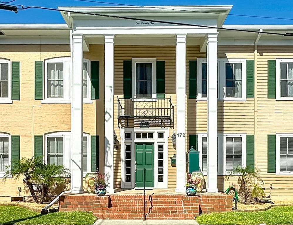 ein großes Haus mit grüner Tür und weißen Säulen in der Unterkunft Cozy Quiet St Augustine Private Condo - 2bed, 1 bath, Sleeps 6, Steps to Historic St Augustine Center & All Tourist Attractions, Restaurants, Cafes, Backyard, Porch in St. Augustine