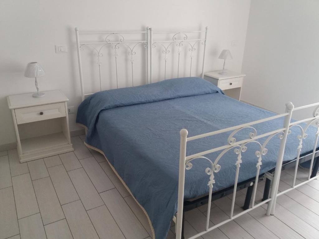 a white bed with a blue blanket and two night stands at Casa Regina Elena II in Termoli