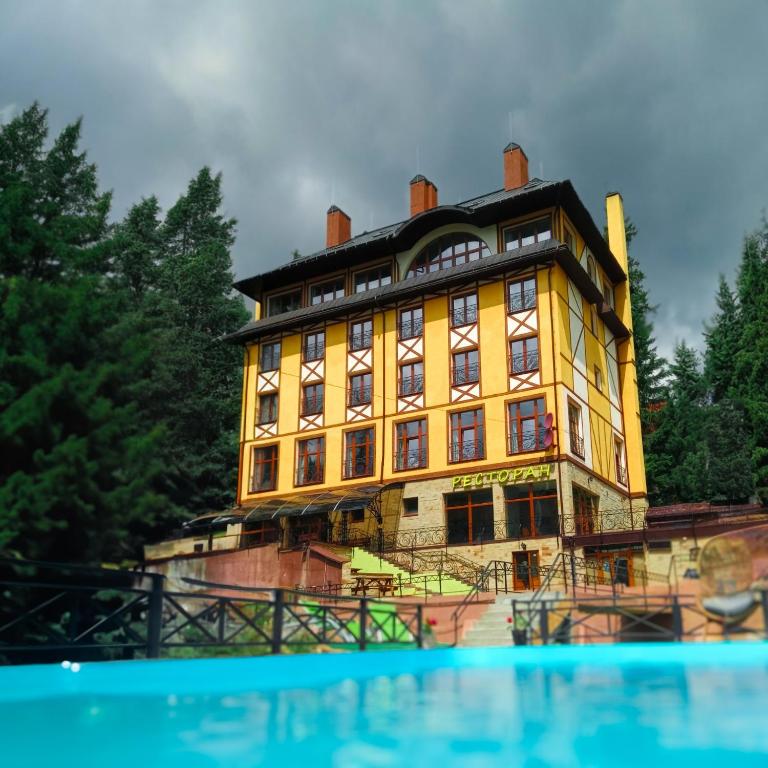 a large yellow building with trees in the background at Готель Вілла Драгобрат in Dragobrat