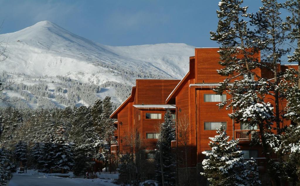 a building with a snow covered mountain in the background at Pine Ridge Condominiums in Breckenridge