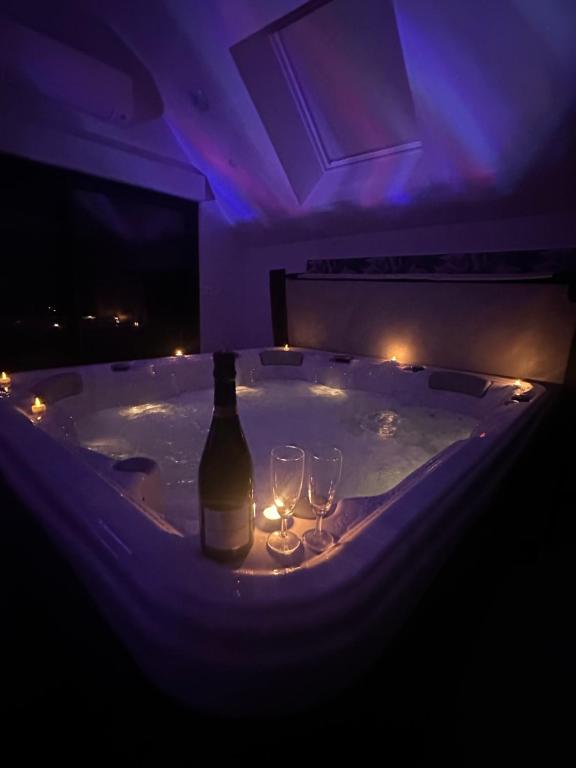 - une baignoire avec une bouteille de vin et 2 verres à vin dans l'établissement L'évasion, à Martainneville