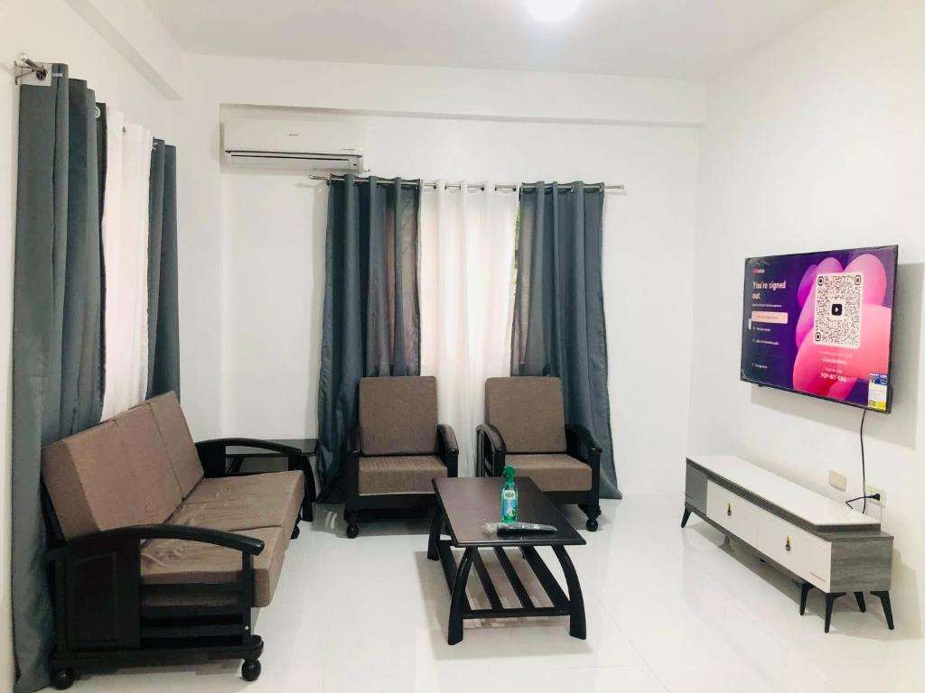 ein Wohnzimmer mit Stühlen und einem Tisch und einem Fernseher in der Unterkunft Sammys House Rental in Puerto Galera