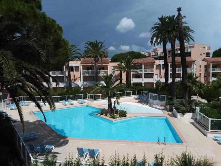 une grande piscine avec des palmiers et des bâtiments dans l'établissement APP RDC GRANDE TERRASSE 43 m2 air-conditioned apartment MAX 6 PEOPLE, à Vallauris